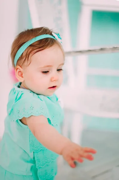 Adorável menina rindo, sorrindo, rastejando e brincando no estúdio vestindo vestido de hortelã — Fotografia de Stock