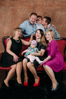 Üç nesil aile birlikte kanepede oturuyor. Klasik portre