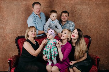 Üç nesil aile birlikte kanepede oturuyor. Klasik portre