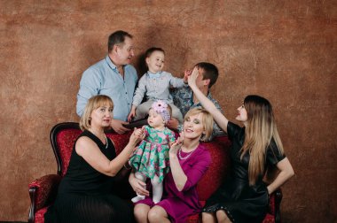 Üç nesil aile birlikte kanepede oturuyor. Klasik portre