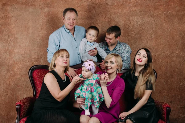 Üç nesil aile birlikte kanepede oturuyor. Klasik portre