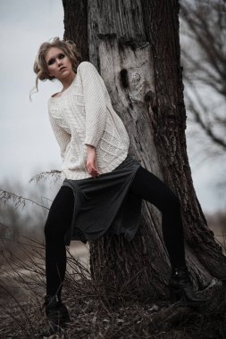 güzel sarışın genç kadın bahar arka plan, orman, göl, ağaçlar üzerinde beyaz kazak uzun etekle mavi gözlü. Soğuk ruh hali. Moda, duygusal portre