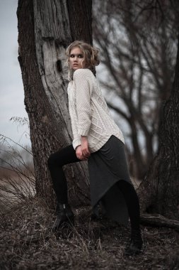 güzel sarışın genç kadın bahar arka plan, orman, göl, ağaçlar üzerinde beyaz kazak uzun etekle mavi gözlü. Soğuk ruh hali. Moda, duygusal portre