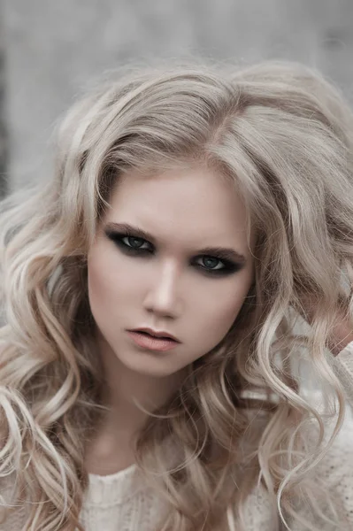 Gros plan de belle jeune femme blonde aux yeux bleus en pull blanc . — Photo