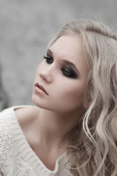 Close up van mooie jonge blonde vrouw met blauwe ogen in de witte trui. — Stockfoto
