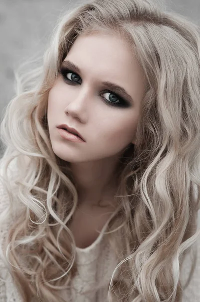 Zbliżenie na pięknej młodej kobiety Blondynka o niebieskich oczach w biały sweter. — Zdjęcie stockowe