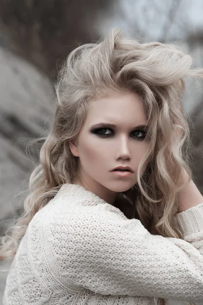 Nahaufnahme einer schönen jungen blonden Frau mit blauen Augen im weißen Pullover. — Stockfoto