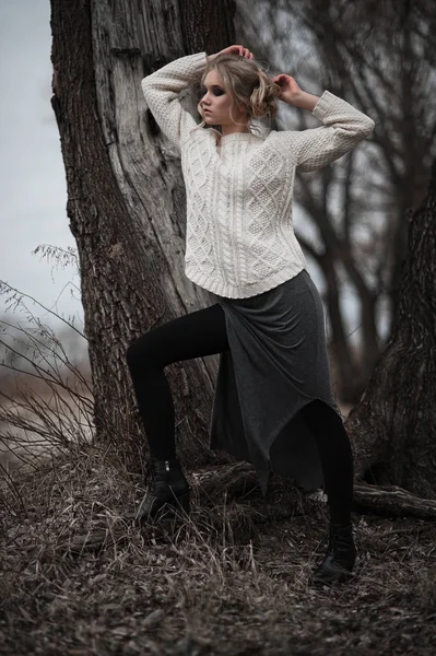 Bela jovem mulher loira com olhos azuis em pulôver branco saia longa no fundo da primavera, floresta, lago, árvores. Humor frio. Moda, retrato emocional — Fotografia de Stock