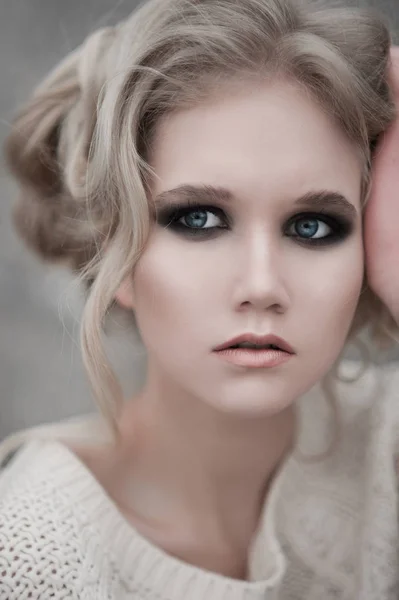 Gros plan de belle jeune femme blonde aux yeux bleus en pull blanc . — Photo