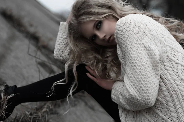 Красива молода блондинка з блакитними очима в білому пуловері довга спідниця на весняному тлі, лісі, озері, деревах. Холодний настрій. Мода, емоційний портрет — стокове фото