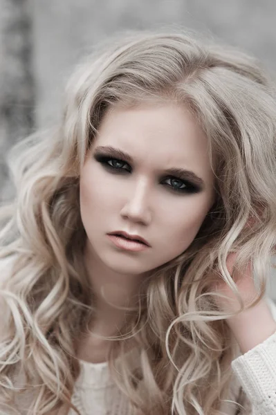 Крупным планом красивая молодая блондинка с голубыми глазами в белом свитере . — стоковое фото