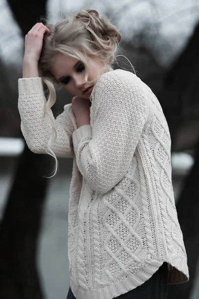 Mooie jonge blonde vrouw met blauwe ogen in de witte trui lange rok op voorjaar achtergrond, bomen, bos, lake. Koude sfeer. Mode, emotionele portret — Stockfoto