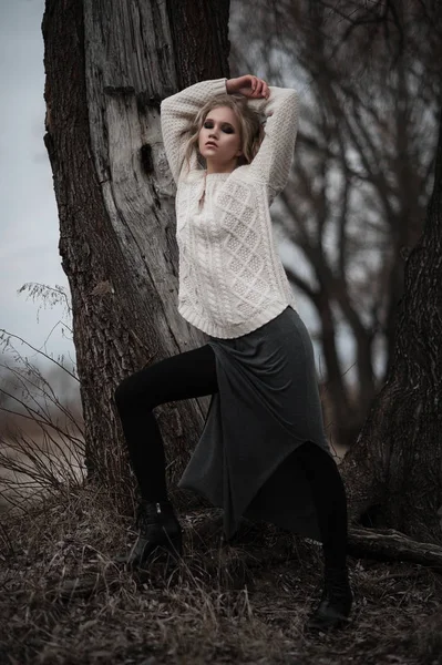 Bela jovem mulher loira com olhos azuis em pulôver branco saia longa no fundo da primavera, floresta, lago, árvores. Humor frio. Moda, retrato emocional — Fotografia de Stock