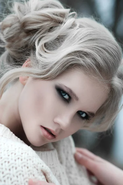 Nahaufnahme einer schönen jungen blonden Frau mit blauen Augen im weißen Pullover. — Stockfoto
