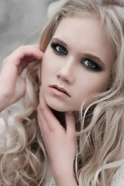 Close up van mooie jonge blonde vrouw met blauwe ogen in de witte trui. — Stockfoto