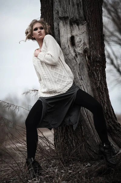 Mooie jonge blonde vrouw met blauwe ogen in de witte trui lange rok op voorjaar achtergrond, bomen, bos, lake. Koude sfeer. Mode, emotionele portret — Stockfoto