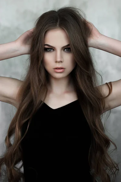 Νεαρή κοπέλα με μακριά όμορφα μαλλιά και καπνιστή μάτια φορώντας μαύρο maxi φόρεμα βράδυ. Studio που γυρίστηκε — Φωτογραφία Αρχείου