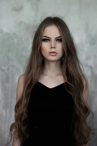 Jeune fille aux longs beaux cheveux et aux yeux fumés portant une robe de soirée maxi noire. Plan studio — Photo