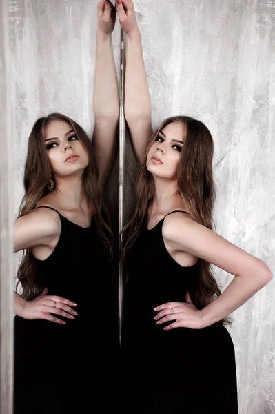 Chica joven con el pelo largo y hermoso y ojos ahumados usando maxi vestido de noche negro posando con un espejo. Captura de estudio —  Fotos de Stock