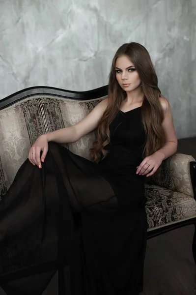 Jeune fille aux longs beaux cheveux et aux yeux fumés portant une robe de soirée maxi noire. Plan studio — Photo