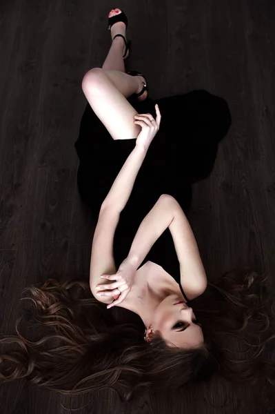 Chica joven con el pelo largo y hermoso y ojos ahumados usando maxi vestido de noche negro posando con un espejo. Captura de estudio —  Fotos de Stock