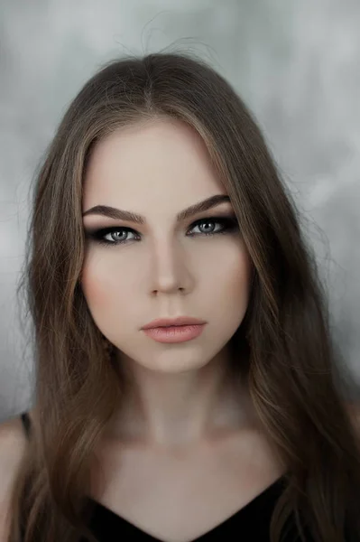 Jeune fille aux longs beaux cheveux et aux yeux fumés portant une robe de soirée maxi noire. Plan studio — Photo