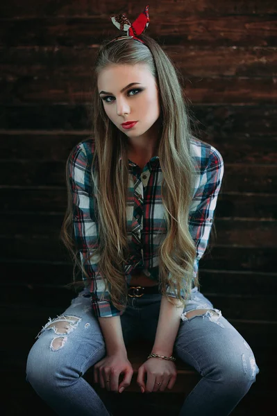 Atraktivní mladá dívka s úsměvem země pohledem, studio střílel, americká country stylu. Dřevěné pozadí — Stock fotografie