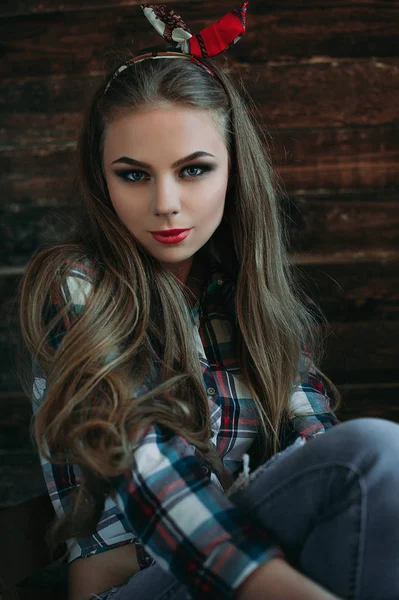 Menina jovem atraente sorrindo com aparência de país, tiro de estúdio, estilo country americano. Fundo de madeira — Fotografia de Stock