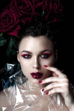 Güzellik moda Model kadın yüzü. Öğe, dikey, kırmızı gül çiçekler. Kırmızı dudaklar ve çivi. Güzel esmer kadın lüks makyaj, cilt mükemmel. Sevgililer.