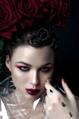 Güzellik moda Model kadın yüzü. Öğe, dikey, kırmızı gül çiçekler. Kırmızı dudaklar ve çivi. Güzel esmer kadın lüks makyaj, cilt mükemmel. Sevgililer.