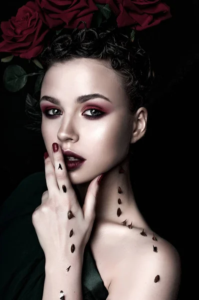 Güzellik moda Model kadın yüzü. Öğe, dikey, kırmızı gül çiçekler. Kırmızı dudaklar ve çivi. Güzel esmer kadın lüks makyaj, cilt mükemmel. Sevgililer.