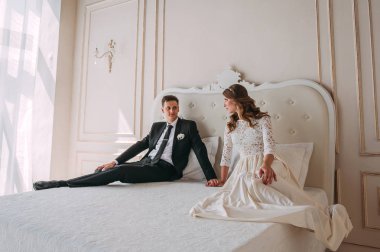 iç şirin düğün birkaç yatağı üzerinde poz bir klasik beyaz stüdyo dekore edilmiştir. Hey öp ve, birbirine bakarak elele sarılmak