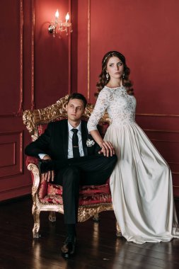 kırmızı arka plan ile klasik bir stüdyo tatlı düğün birkaç iç. Hey öp ve, birbirine bakarak elele sarılmak