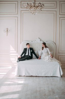 iç şirin düğün birkaç yatağı üzerinde poz bir klasik beyaz stüdyo dekore edilmiştir. Hey öp ve, birbirine bakarak elele sarılmak