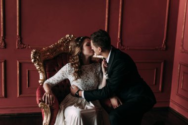 kırmızı arka plan ile klasik bir stüdyo tatlı düğün birkaç iç. Hey öp ve, birbirine bakarak elele sarılmak