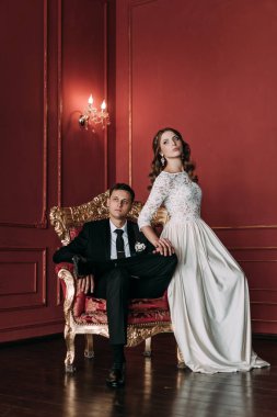 kırmızı arka plan ile klasik bir stüdyo tatlı düğün birkaç iç. Hey öp ve, birbirine bakarak elele sarılmak