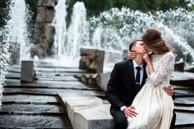 Gelin ve damat öpüşme ile arka planda çeşme