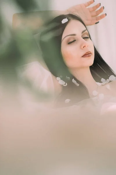 Portrait of young dark-haired woman in the flowered garden in th — Stock Photo, Image