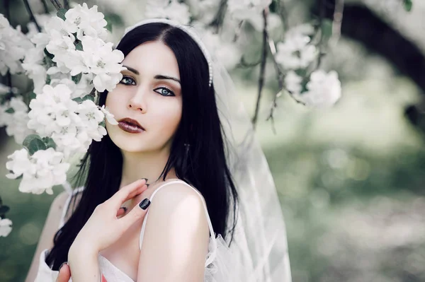 Portrait of young dark-haired woman in the flowered garden in th — Stock Photo, Image