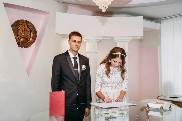 A gyönyörű menyasszony és a vőlegény jóképű esküvői regisztráció során — Stock Fotó