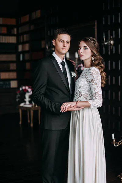 Casal de casamento bonito no interior de um estúdio clássico decorado. Beijar e abraçar um ao outro — Fotografia de Stock