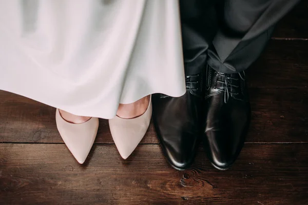 Amor y felicidad el día de la boda. Primer plano de pies y zapatos de novia y novio y decoración de madera 'amor' en sus manos . — Foto de Stock