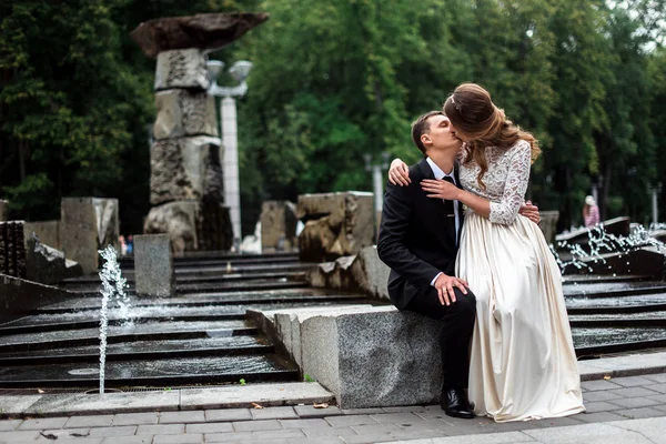 Braut und Bräutigam küssen sich mit dem Brunnen im Hintergrund — Stockfoto