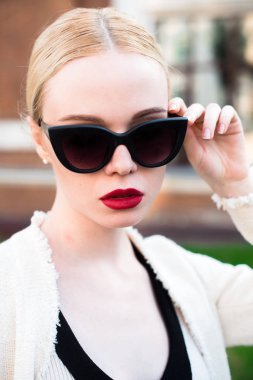 Mutlu moda sarışın Avrupa zarif kadın kırmızı dudakları ve beyaz ayakta yeşil çimenlerin üzerinde bina eski kırmızı tuğla, Cilt. Seksi kız açık havada. Resmi siyah beyaz elbiseli güzel kadın 