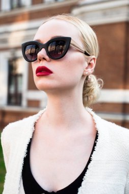 Mutlu moda sarışın Avrupa zarif kadın kırmızı dudakları ve beyaz ayakta yeşil çimenlerin üzerinde bina eski kırmızı tuğla, Cilt. Seksi kız açık havada. Resmi siyah beyaz elbiseli güzel kadın 