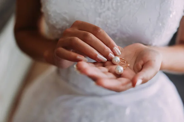 Una novia está sosteniendo las hermosas joyas (pendientes, colgante) en la mano — Foto de Stock