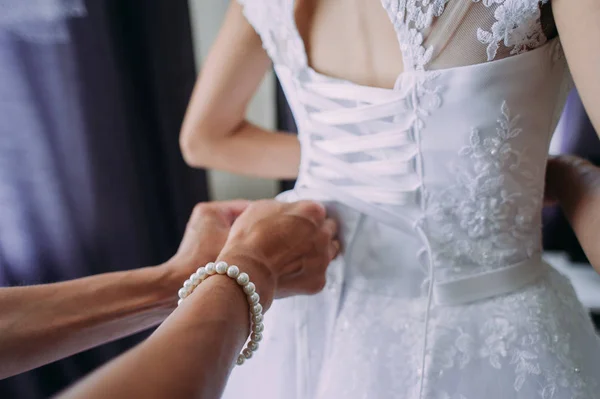 Bruidsmeisje koppelverkoop boog op trouwjurk — Stockfoto