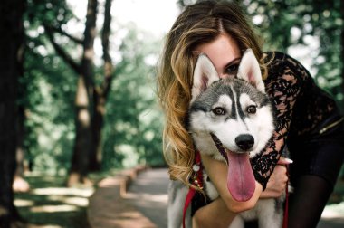 Siberian dış yapraklar kızla. Güzel kız Siberian dış yapraklar ile oynuyor. Kız ile bir av köpeği - Batı Sibirya husky yürüyüş. Yakın çekim. Moda fotoğraf, siyah ve beyaz vurdu.