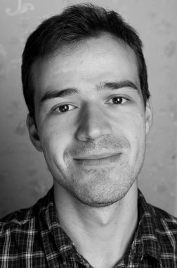 Gri arka planda kameraya poz veren yakışıklı bir adamın siyah beyaz portresi.