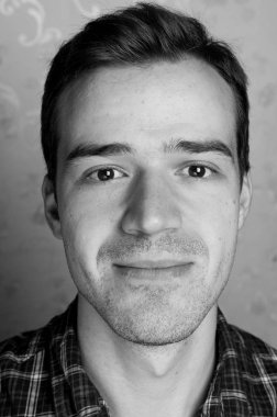 Gri arka planda kameraya poz veren yakışıklı bir adamın siyah beyaz portresi.